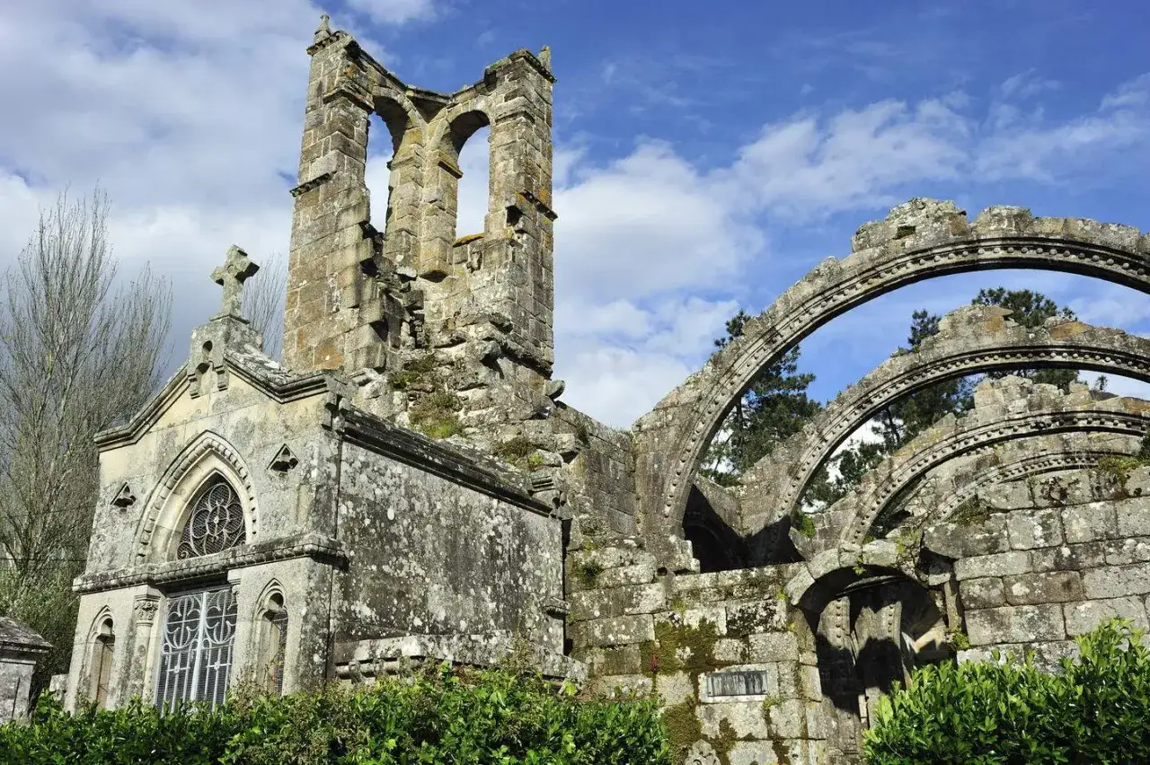 Ruinas de piedra con arcos y una cruz, un lugar histórico para visitar Galicia.