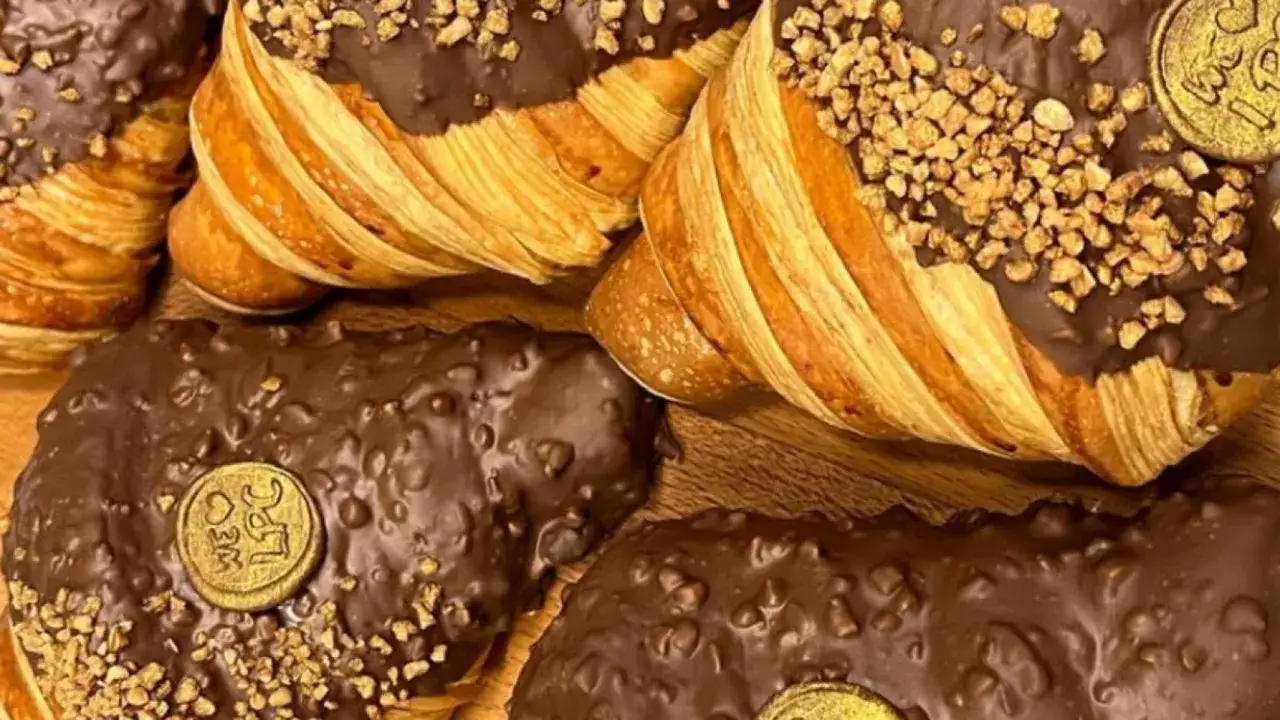 Deliciosos croissants bañados en chocolate y almendras, con un toque dorado que recuerda a Zaragoza.