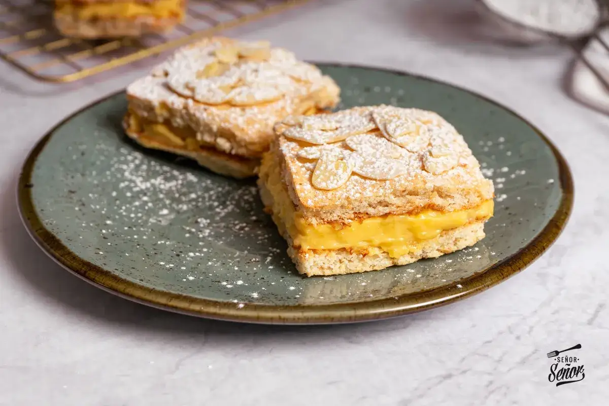 Pastel ruso, un postre con origen en Europa del Este, con capas de bizcocho y crema, cubierto de almendras laminadas y azúcar glas.