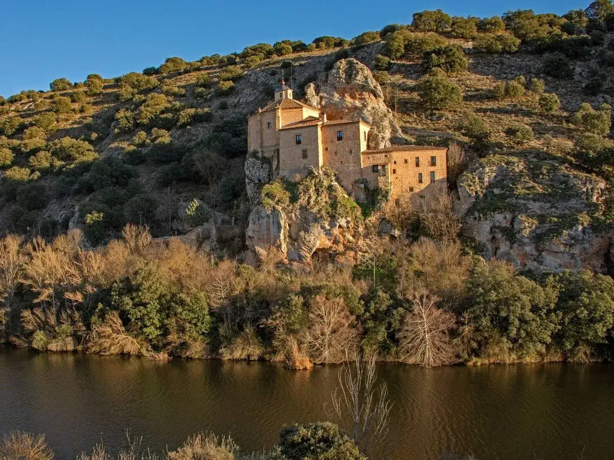Monasterio rupestre en un acantilado junto a un río. Un lugar que merece la pena visitar Soria por su belleza natural e histórica.