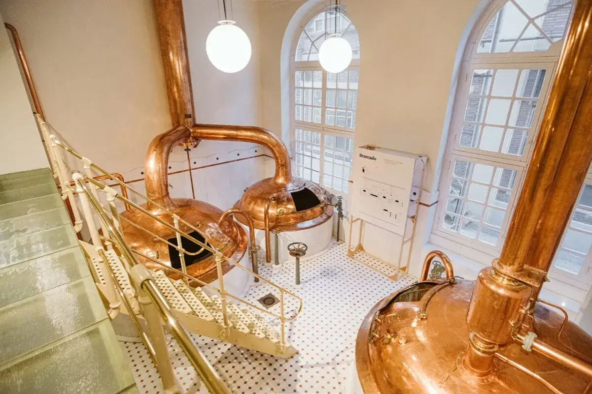 Cata de cervezas Zaragoza: Cobre brillante y escaleras metálicas en una cervecería tradicional.