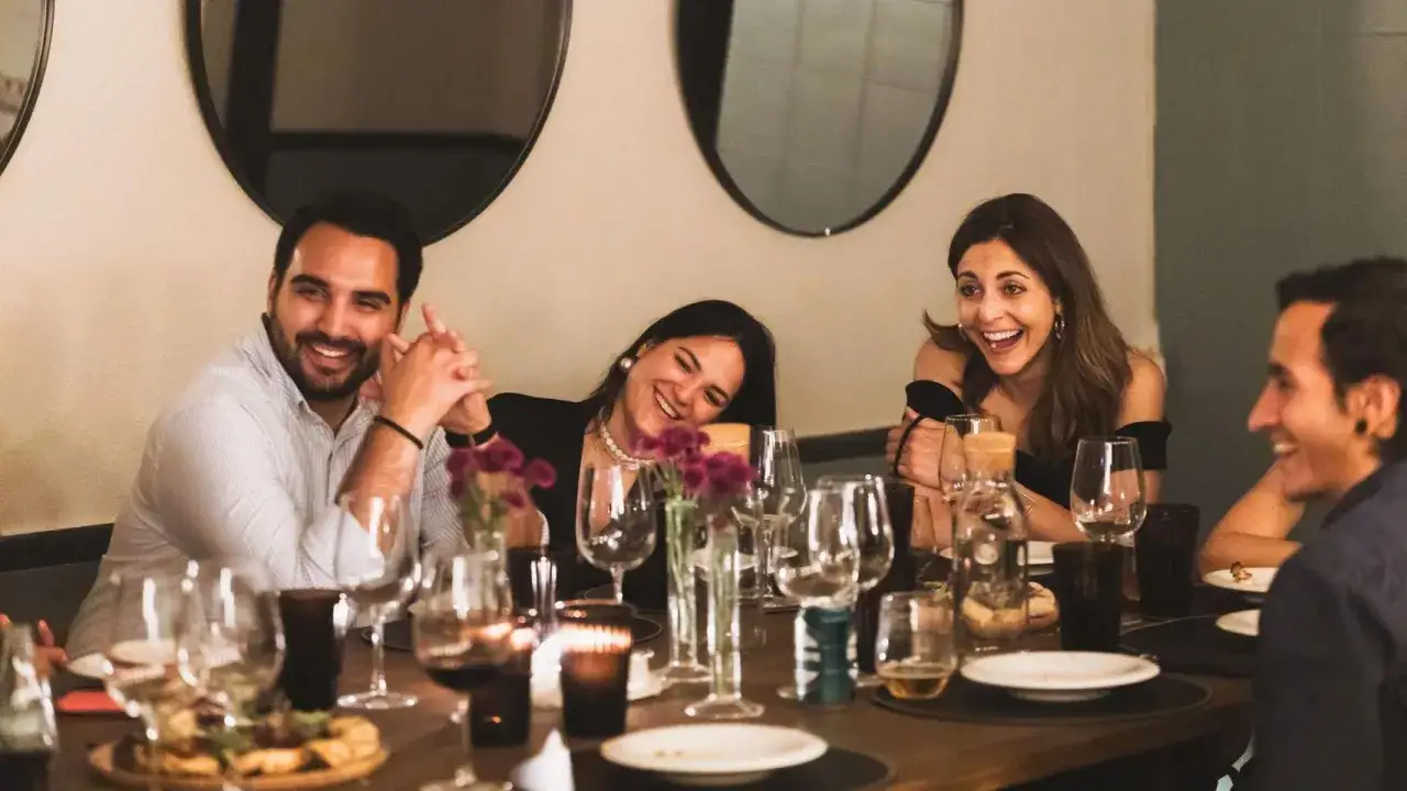 Amigos riendo en una cena. Las timeleft opiniones sobre este restaurante son muy positivas, ¡se nota la alegría!
