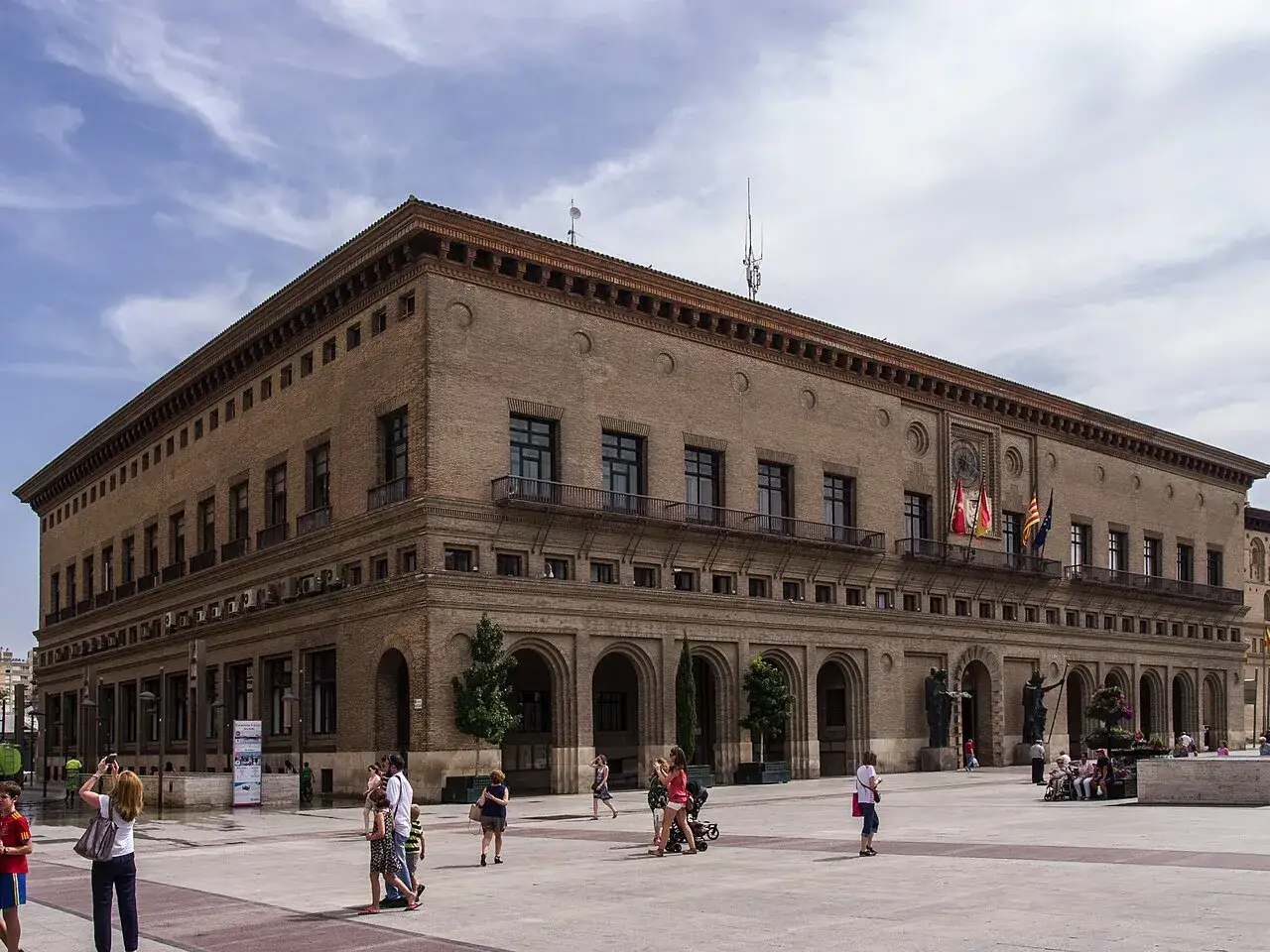 El ayuntamiento en la plaza del Pilar, Zaragoza, con gente paseando y haciendo fotos.