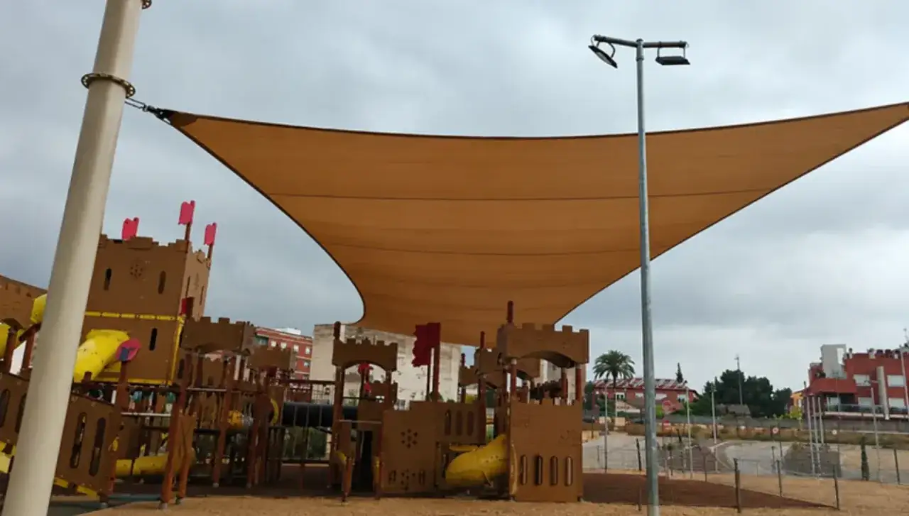 Castillo de juegos infantiles con toboganes amarillos, bajo una gran vela de sombra. Un lugar ideal para jugar en el parque de bolas Zaragoza.