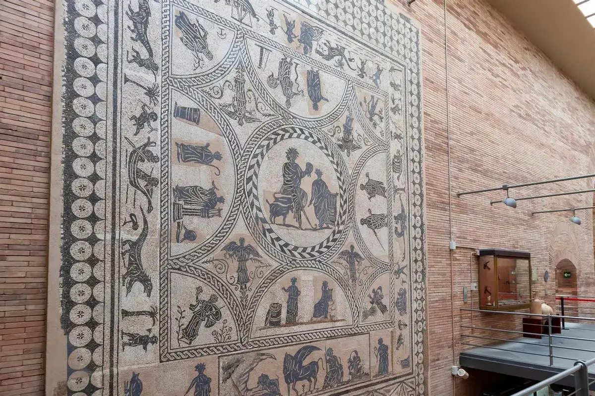 Mosaico romano expuesto en un museo, con escenas mitológicas y figuras humanas.