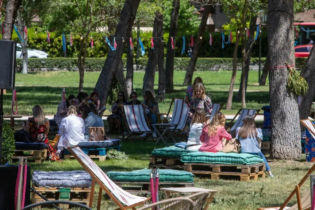 Un grupo de mujeres disfruta de un día de picnic Zaragoza, sentadas en cojines sobre palets en un parque.