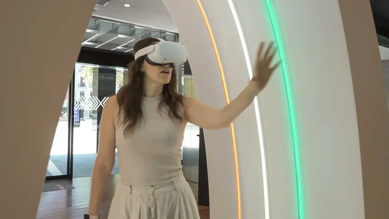 Mujer con gafas de RV interactuando en el espacio Xplora Ibercaja, tocando una luz verde.