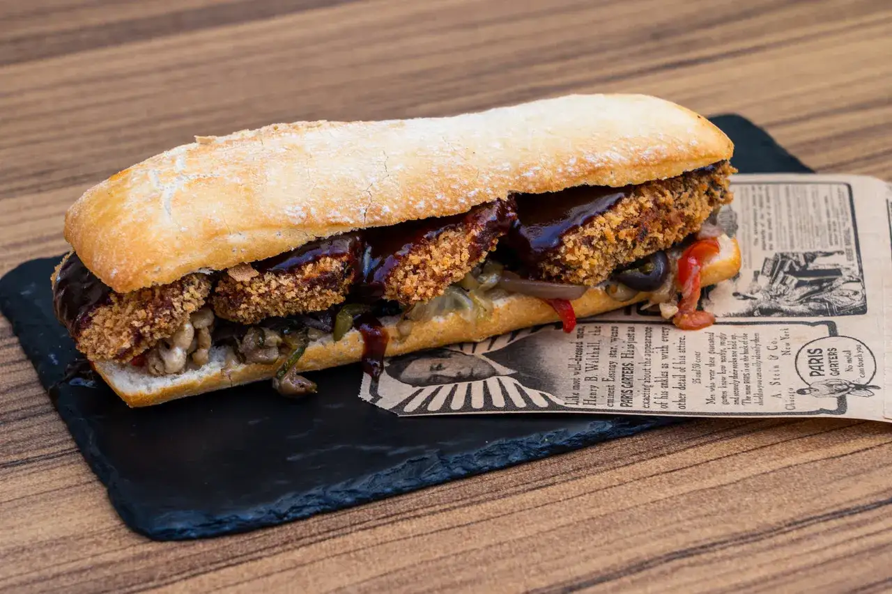 Un bocadillo generoso con rebozado crujiente, salsa barbacoa y verduras salteadas, uno de los mejores bocadillos de Zaragoza.