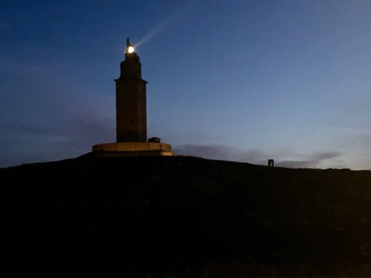 Torre de Hércules iluminada al anochecer, un lugar imprescindible que visitar en A Coruña.