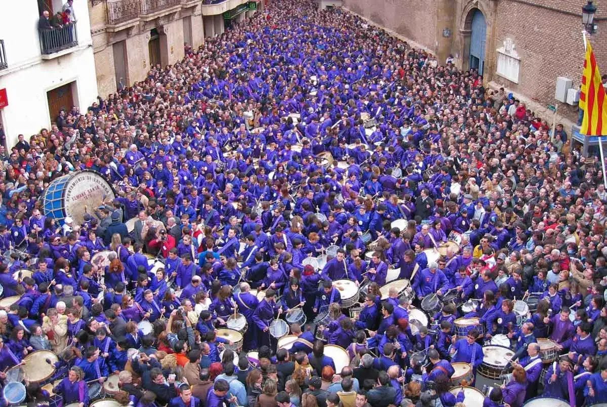 Multitudinaria procesión en Zaragoza, con cientos de personas vestidas de morado tocando tambores y bombos.