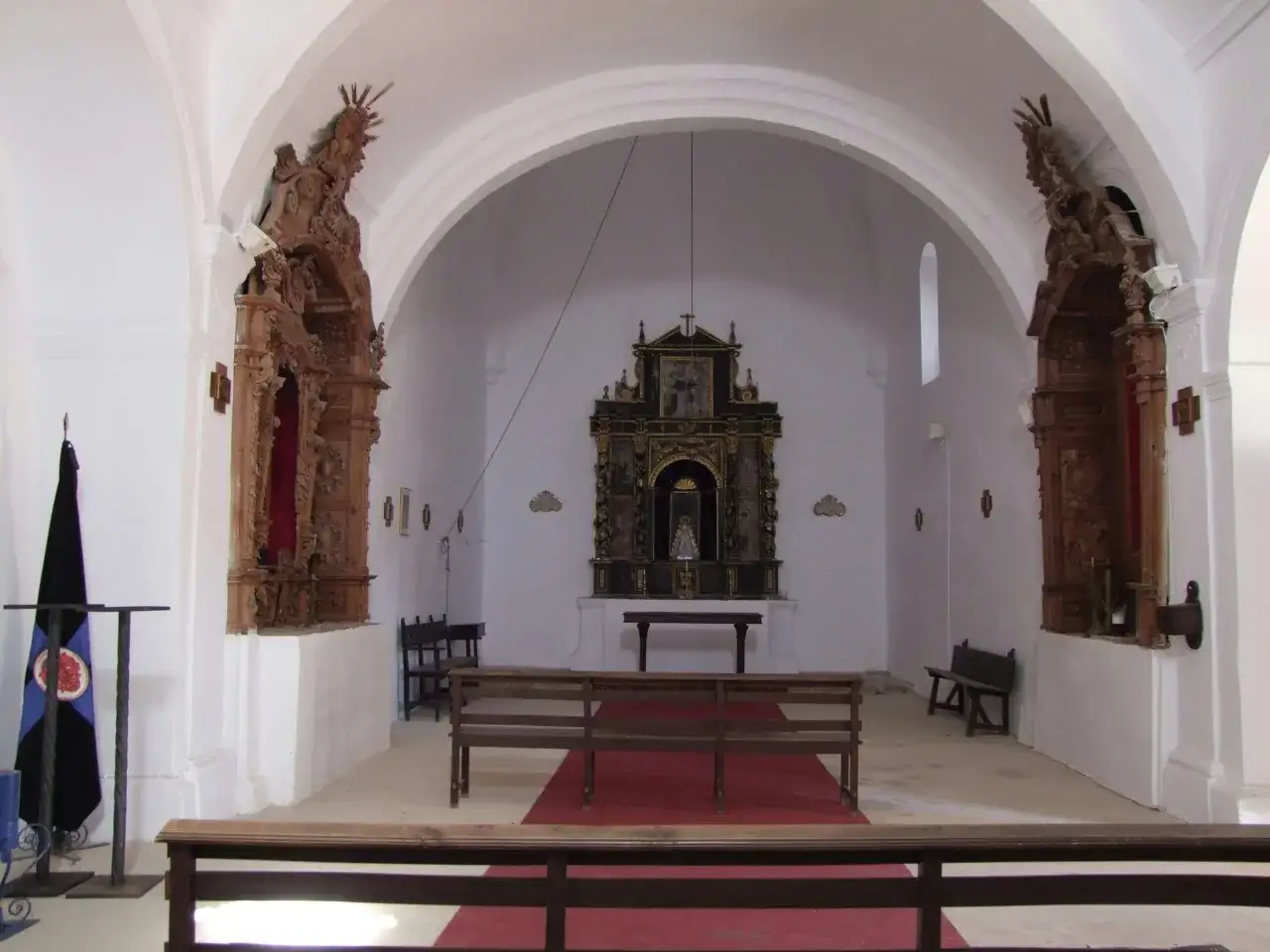 Interior de la iglesia Nuestra Señora de Gracia, con bancos de madera, un altar principal y retablos laterales.