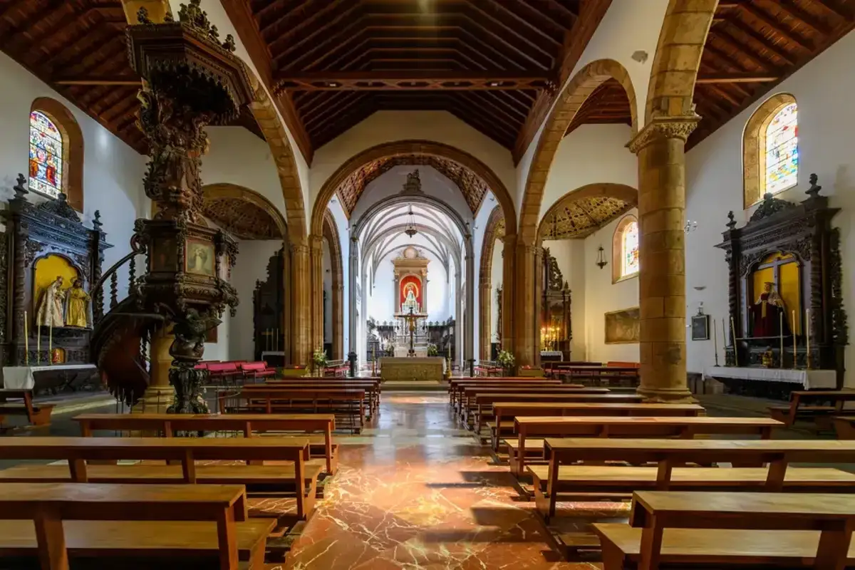 Interior de una iglesia con bancos de madera, un púlpito tallado y un altar. Podría ser la mejor catedral de España.