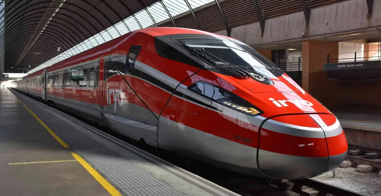 El moderno tren iryo de color rojo y plateado espera en la estación de Sevilla Santa Justa, listo para su próximo viaje.