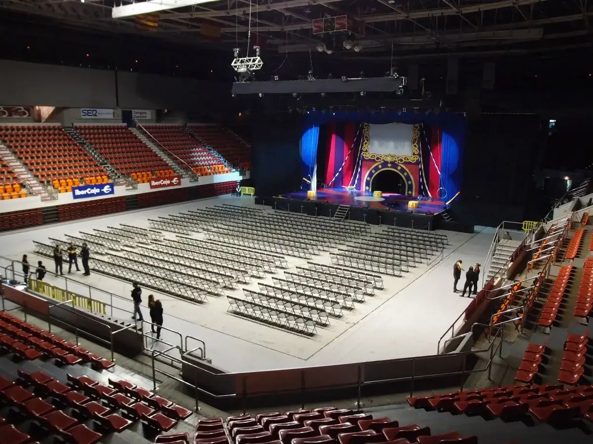 Escenario preparado para pabellón Príncipe Felipe conciertos. Sillas plegables vacías esperan al público.