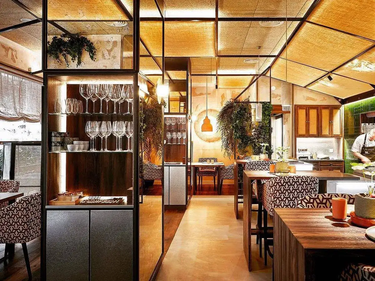 Interior de un restaurante estrella Michelin con mesas de madera, sillas estampadas y estanterías de cristal con copas.