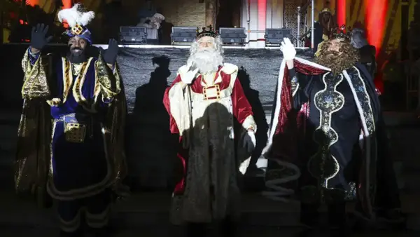 Los Reyes Magos saludan al público en la cabalgata de Reyes de Huesca, con sus trajes brillantes y coronas.