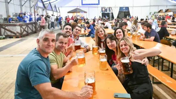 Amigos brindando con jarras de cerveza en el oktober valdespartera. Ambiente festivo y sonrisas.