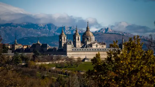 Impresionante Monasterio de El Escorial, un lugar clave que ver en la Comunidad de Madrid, con montañas nevadas al fondo.