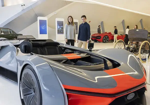 Jóvenes observan coches futuristas y clásicos en una exposición de coches en Zaragoza.