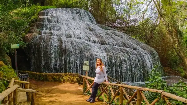 Cascada espectacular, ideal para descubrir qué ver cerca de Calatayud. Una mujer sonríe apoyada en una barandilla de madera.