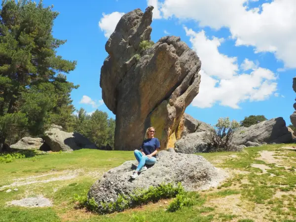 Mujer sentada en roca, con imponente formación rocosa detrás. Un paisaje natural que demuestra que merece la pena visitar Soria.