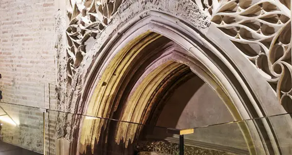Detalle arquitectónico de un arco gótico en el museo Alma Mater, con ladrillo expuesto y ornamentación de piedra calada.