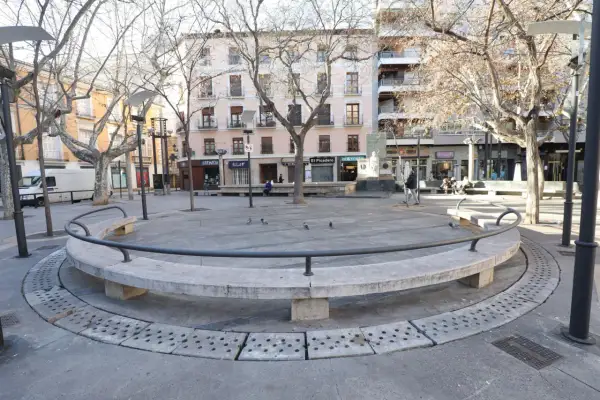 Banqueta circular de piedra en la plaza San Pedro Nolasco Zaragoza, con árboles desnudos y edificios al fondo.