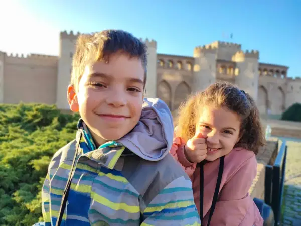 Dos niños sonríen frente a un palacio en Zaragoza. ¡Una aventura familiar en el museo!