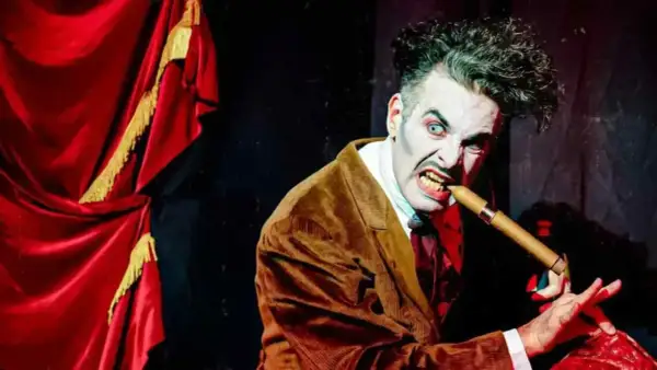 Actor con maquillaje de terror y traje marrón muerde un puro, listo para el circo del terror Zaragoza.