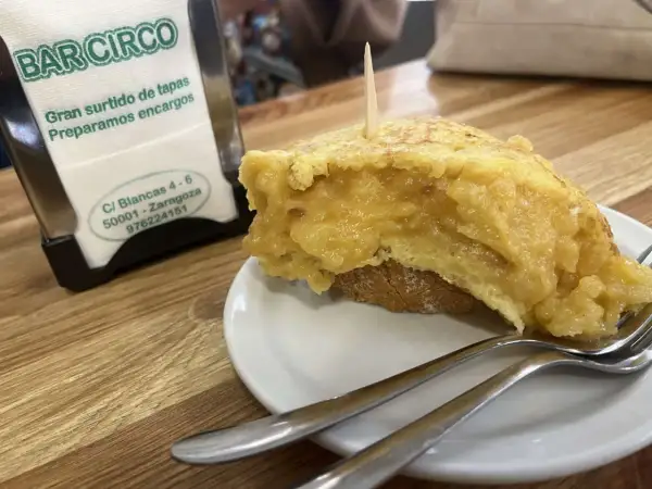 Deliciosa tortilla de patata zaragozana en Bar Circo, lista para disfrutar con tenedores.
