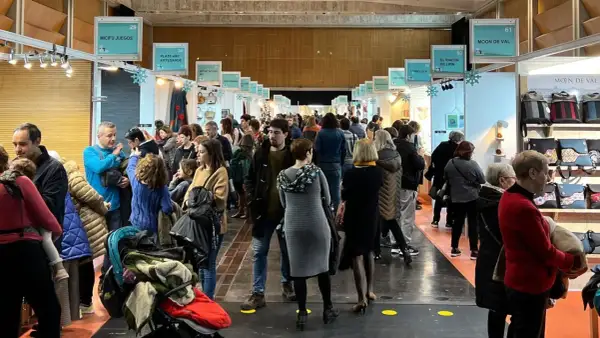 Gente disfrutando de la feria artesanía Zaragoza, con puestos de juegos, arte y bolsos.