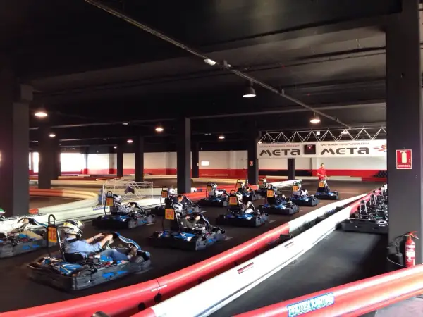 Carreras de **karting Puerto Venecia**. Varios karts listos en la pista, algunos con pilotos preparándose para la acción.