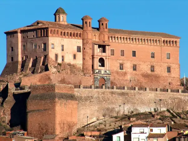Imponente castillo Zaragoza, con sus torres y cúpulas, se alza sobre una colina rocosa, vigilando el paisaje.