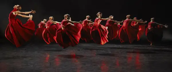 Danzarinas con vestidos rojos vibrantes en el escenario, evocando la fuerza de Carmina Burana en Zaragoza.