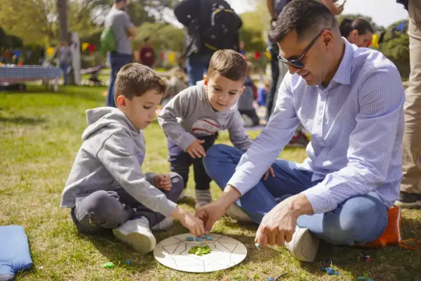 Un padre y sus hijos disfrutan de un juego en el césped, creando un momento familiar entre las tribus del parque Zaragoza.