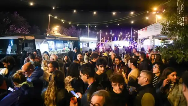 Multitud disfrutando de food trucks Zaragoza Pilares bajo luces festivas.
