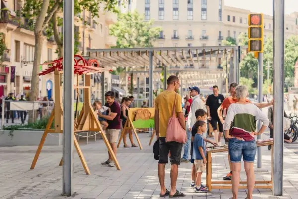 Gente disfrutando de unas vacaciones con niños en Cataluña, con juegos y actividades al aire libre en una calle peatonal.