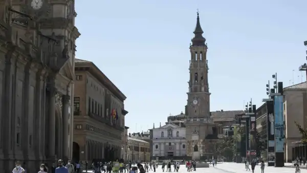 Plaza del Pilar en Zaragoza, con la imponente iglesia de la Seo y el Ayuntamiento. Gente paseando bajo el sol.