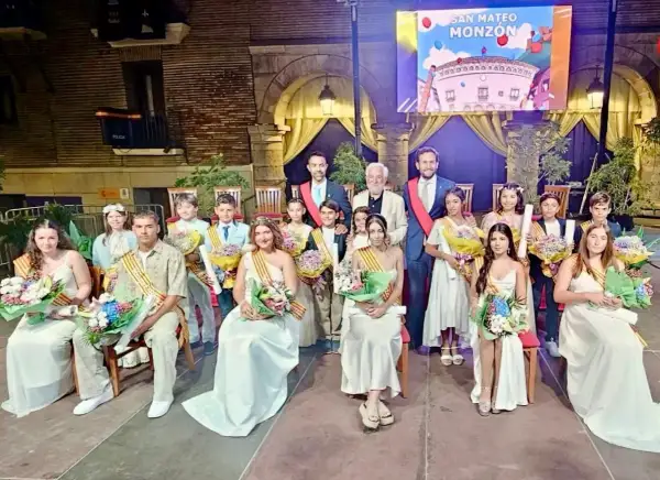 Jóvenes y adultos celebran las fiestas de Monzón, luciendo trajes elegantes y portando ramos de flores.