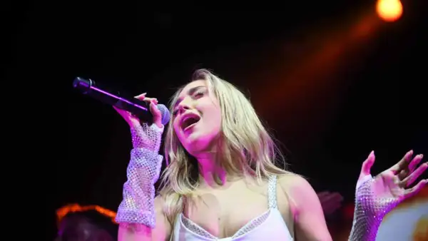 Ana Mena canta en Zaragoza, con un micrófono en la mano y guantes brillantes.