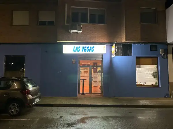 Fachada de "Las Vegas" en Zaragoza, con un coche aparcado y la calle mojada.