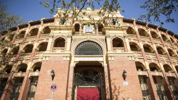 La imponente fachada de la plaza de toros de Zaragoza, con sus arcos y balcones, se alza bajo un cielo azul.
