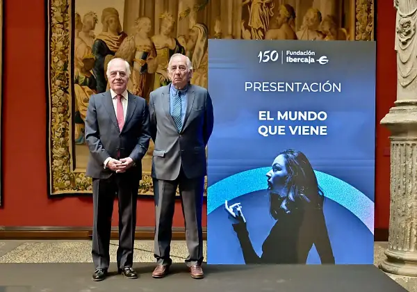 Dos hombres de traje posan ante un cartel de Fundación Ibercaja que anuncia "El mundo que viene", en un evento de martes de libros Ibercaja.