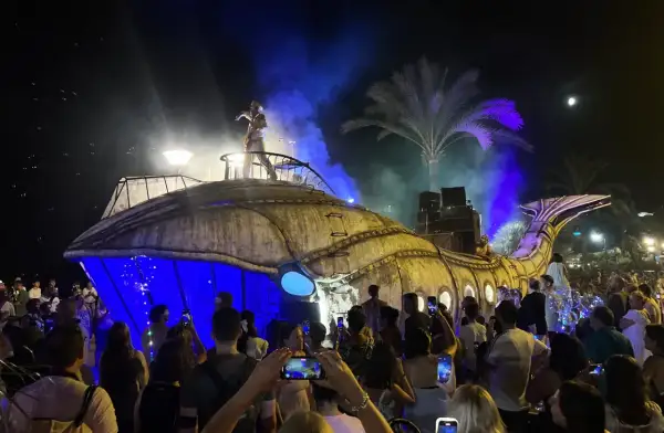 Una gran ballena mecánica ilumina la noche en una fiesta de los 90 en Zaragoza. El público, con móviles en mano, celebra el espectáculo.