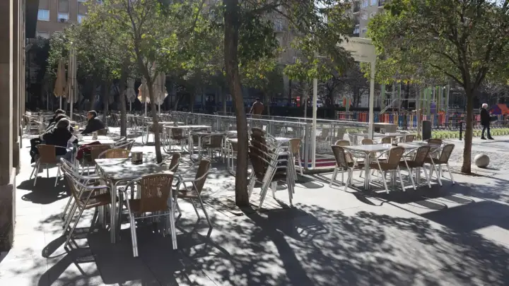 Mesas y sillas vacías en la terraza de bares de la plaza San Francisco, bajo la sombra de los árboles.